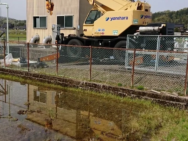富山の株式会社エイキ　アスベスト部品付き巨大配管の撤去工事　クレーンで吊り上げて撤去中