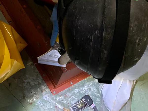 フランジに付着したパッキンをスクレーパーで剥がしている様子