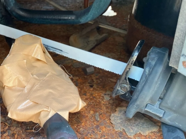 富山でレベル3小型パッキンのアスベスト除去。湿潤化と養生の後、レシプロソー（電動の刃物）で切断中の写真