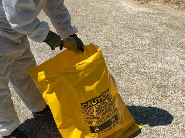 富山でレベル3小型パッキンのアスベスト除去。株式会社エイキの作業員が除去後のアスベストパッキンを袋詰め（1重目）している最中の写真