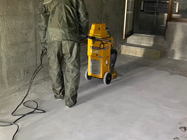 床研削機でアスベスト含有下地材が除去され平滑になった床と、作業員の男性