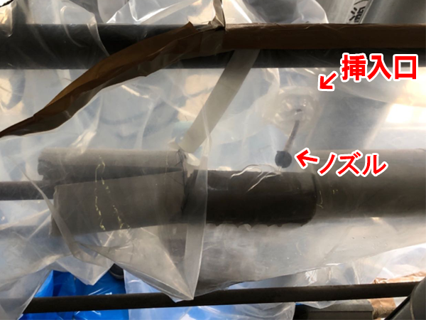 グローブバッグの挿入口から飛散抑制剤を散布中