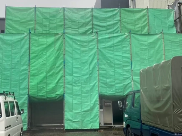 石川県のアスベスト除去現場。富山の株式会社エイキが緑色のシートで建物を養生
