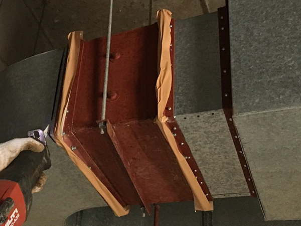 ダクトフランジにあるアスベストパッキンの除去作業風景。フランジのすぐ隣にレシプロソーの刃を入れて、切断している。