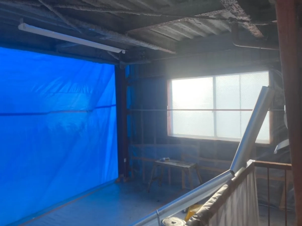 高岡市の公費解体予定の建物でレベル1アスベスト除去。養生後の室内の写真。青いシートで隣の部屋と仕切りが作られている。窓は透明なシートで塞がれている。