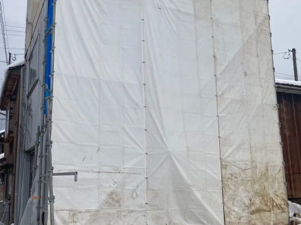 高岡市の公費解体予定の建物でレベル1アスベスト除去。現場を外から撮影した写真。白い防音シートが建物の側面に設置されている