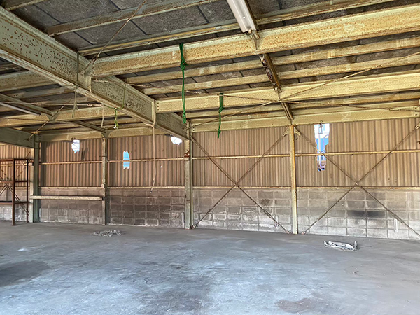 鉄骨が躯体の倉庫の内部。床は土間コンクリートで、基礎はコンクリートブロックとなっており、外壁に波板スレートが取り付けられている。