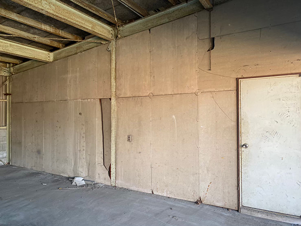 倉庫内の二つの部屋を仕切る壁があり、右側に部屋の出入りができる鉄製のドアがある