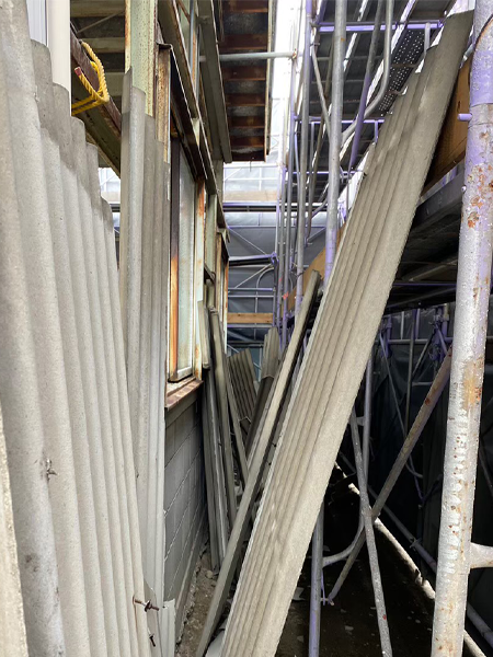 倉庫の外壁として使用されていた波板スレートを取り外し、立て掛けている様子。