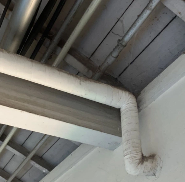 ビルのアスベストの事前調査の様子。白いパイプに保温材がまかれており、その中にアスベストがないか調査している。