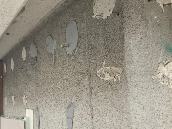 セメント板を取り外し、接着剤と釘が現れたアパートの外壁下地