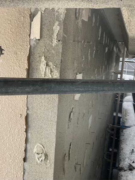 セメント板を取り外し、接着剤と釘が現れたアパート4階の外壁下地