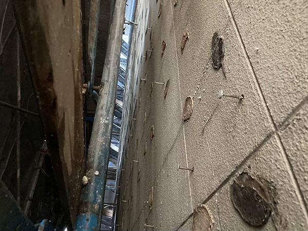 外壁材のセメント板を取り外して下地材のみとなったアパートを1階から見上げた様子