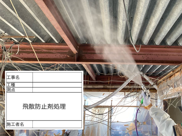 吹き付けアスベストが除去された屋根裏に、飛散防止剤をエアレススプレーで散布している作業員