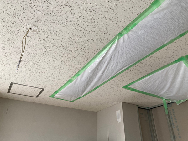 改修予定の部屋の天井。取り外された照明の穴をシートで覆っている。