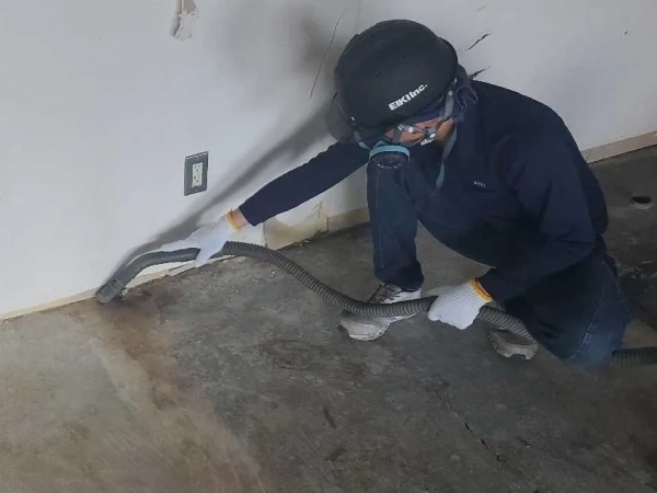 株式会社エイキの従業員が、真空掃除機で養生後の現場を清掃している。