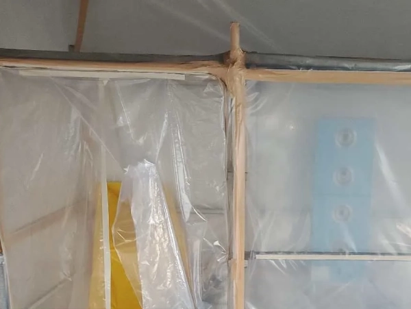 レベル1アスベスト現場のセキュリティゾーン。左が出口、右側が青いエアシャワーユニットが設置された部屋。