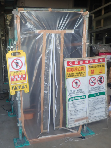 アスベスト除去工事の出入り口となる。セキュリティゾーンの入り口。看板も設置されている。