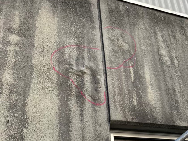 外壁の塗材が二か所浮き出ており、その部分がマーカーで囲まれている。