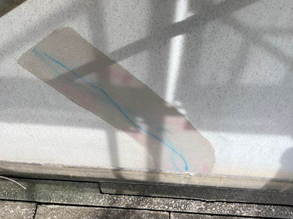 外壁のクラックを記したマーカーを中心に剥離剤を塗布し、その周りの色が変わっている。