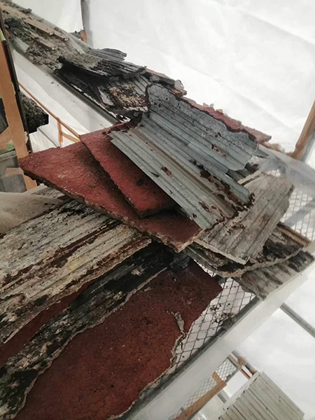 足場の上に重ねて置かれた外壁材。錆びと痛みが激しい