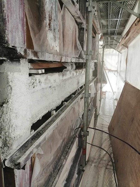 固化剤散布によって白く固化した吹き付けアスベスト。吹き付けアスベストがある鉄骨梁以外の箇所はシートで保護されている。