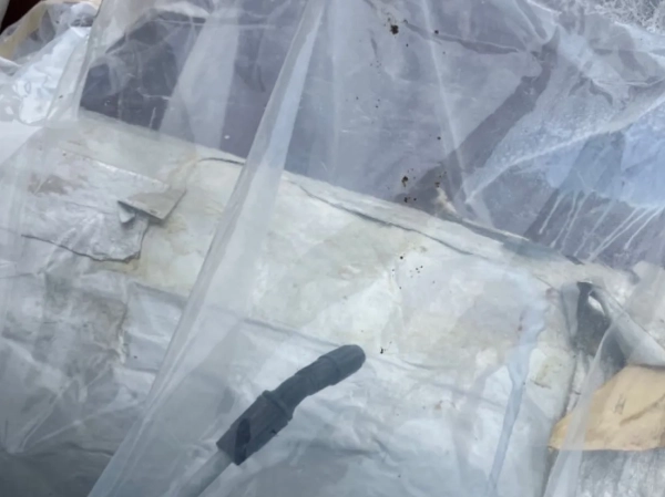 袋の中に噴霧器の先端がある。飛散防止剤を散布して湿潤化中。