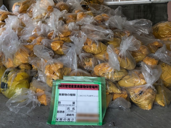 除去済みアスベストの山。前には石綿含有廃棄物を示す看板が置かれている。