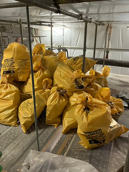 一重梱包された黄色の廃棄袋が現場で一か所にまとめられている。