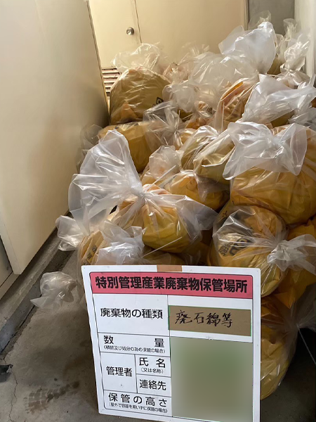 除去済みアスベストの山。前には廃石綿等を示す看板が置かれている。