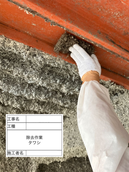 鉄骨に吹き付けられた吹き付けアスベストを、作業員がたわしでこすり落としている。