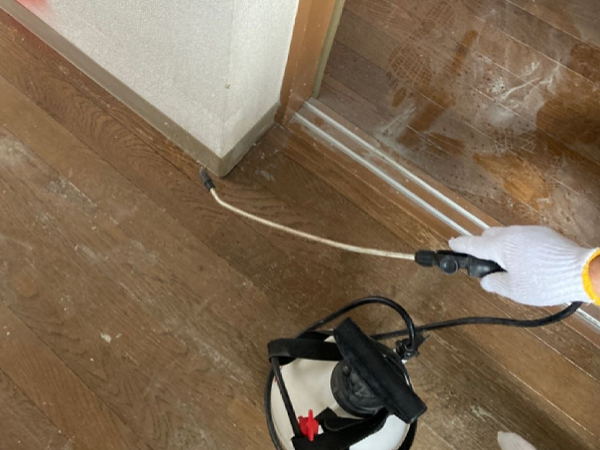噴霧器でアスベスト巾木に飛散抑制剤を散布している。