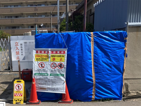 コンクリート壁がアスベスト除去の為に隔離養生されて、シートで覆われている。