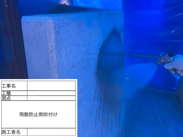 アスベスト塗材を除去したコンクリート壁に飛散防止剤を散布している様子。