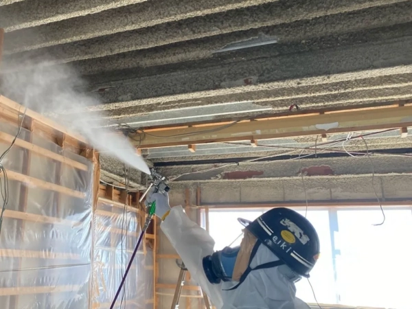 株式会社エイキの作業員が飛散防止剤をアスベストに吹き付けている