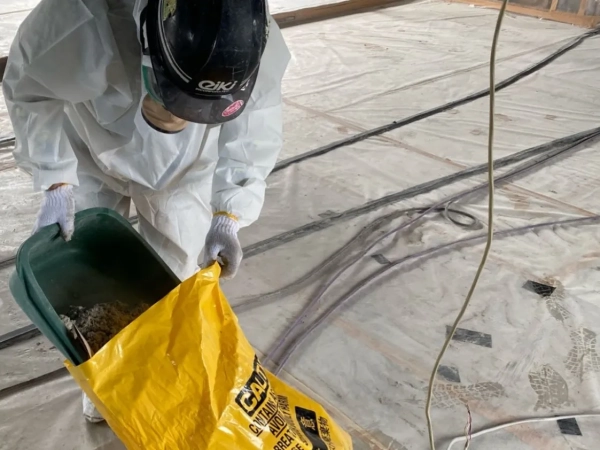 株式会社エイキの作業員が落としたアスベストを黄色の袋に詰めている