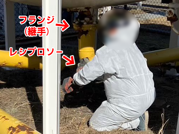 作業員が屋外でレシプロソーを使って配管を切断している。