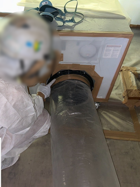 負圧除じん装置と排気ダクトが、接続されているか確認する作業員。