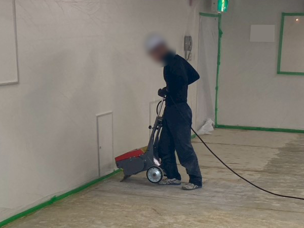 作業員が、床剥がし機を使って剥離作業をしている。