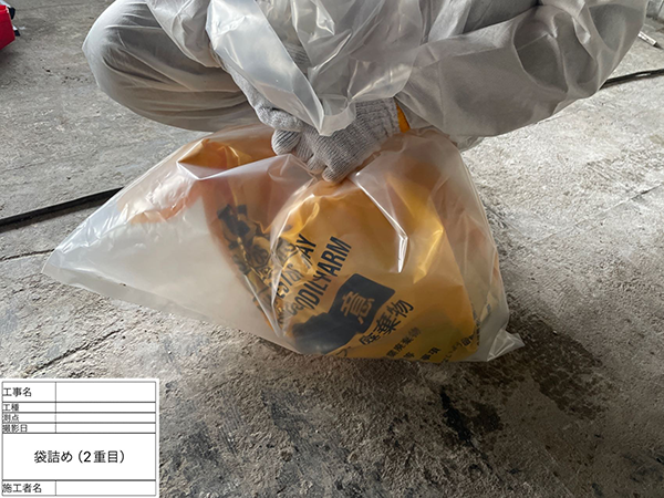 作業員が、配管フランジ入りの廃棄袋を、更に透明の廃棄袋へ梱包している。
