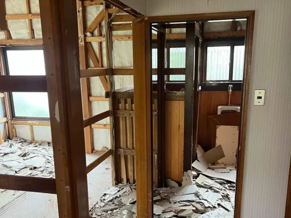 富山県内での解体工事現場で、建物の内部が解体され、柱や梁、そして散乱した内装材の破片が見える写真。