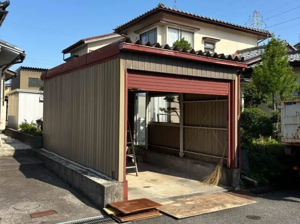 富山の車庫のBefore写真。外材が経年劣化しています。車庫の内部の物品はすでにかたずけられています。脚立と箒が残っているのみです。