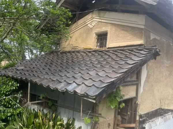 富山の土蔵解体現場。土蔵の外壁の表面が経年劣化が進んでいるのがわります。そばの樹木が土蔵に多い家具去っています。