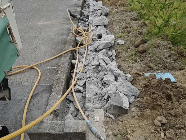 富山の解体現場で電動工具を使って、側溝のコンクリートを細かく砕いている最中の写真。コンクリートの大きさは拳大より大きいものもあれば、破片のように小さなものまであります。
