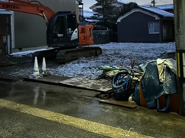 富山市の木造2階建て解体工事現場。株式会社エイキの重機が雨や雪で歪んでしまった地面を整える整地作業をしている際の写真。