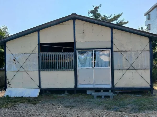富山市内の現場風景。不用品を運び出し、これから本格的な解体に入るプレハブ小屋の外観。正面から撮影。
