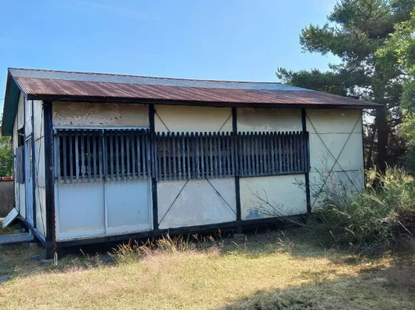 富山市内の現場風景。不用品を運び出し、これから本格的な解体に入るプレハブ小屋の外観です。側面から撮影。