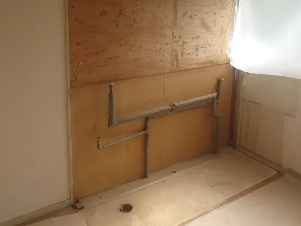 富山で内装解体工事。シンク台撤去後の写真。木材と細いグレーの配管が残っている状態