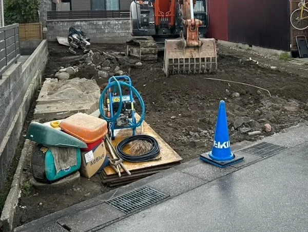住宅本体の解体が終わった段階の写真。地面の上には住宅基礎の破片と重機の交換用アタッチメントが転がっている