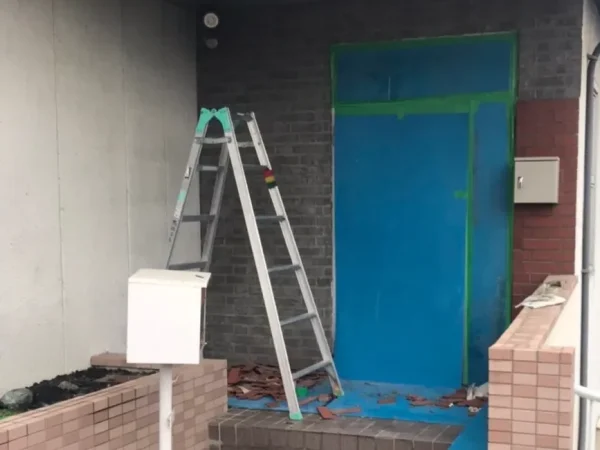 富山でレンガ状の壁タイルを解体。脚立を用意して高所のタイルを解体中の写真